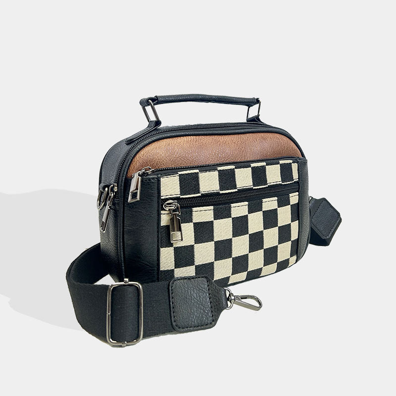 Bolso bandolera compacto negro con frontal de cuadros y cierre con tirador metálico