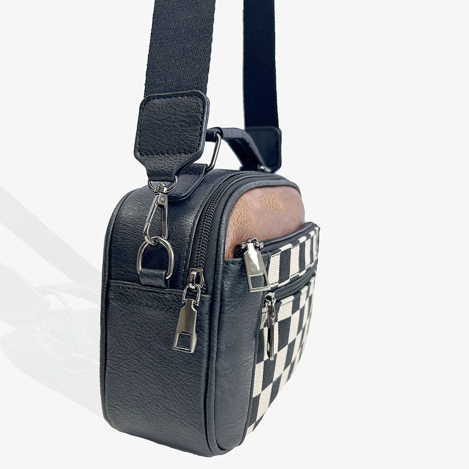 Bolso bandolera compacto negro visto de lado, correa con hebilla y panel de cuadros