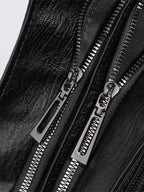 Bolso bandolera de piel sintética negro con cierre de cremallera metálica y tiradores plateados.