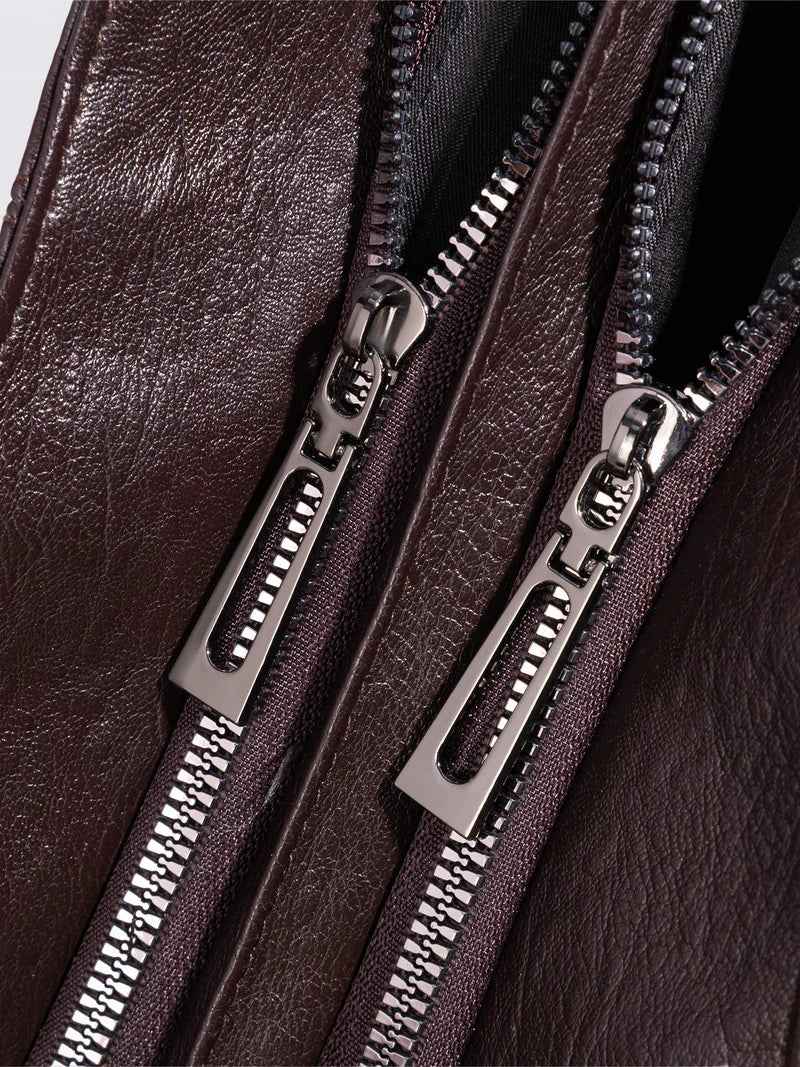 Bolso bandolera de piel sintética marrón con cremalleras metálicas dobles y tiradores plateados.