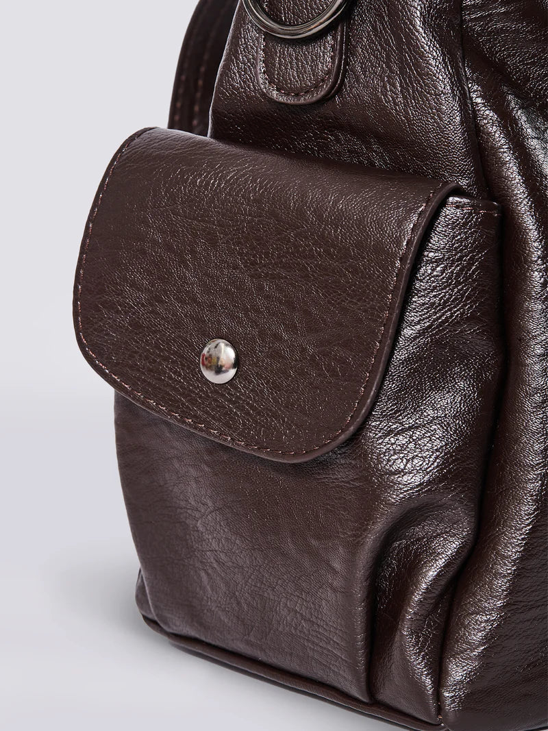 Bolso bandolera de piel sintética marrón con solapa frontal y botón metálico en el bolsillo.