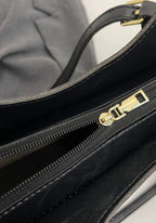 Detalle de cremallera dorada en bolso tote de cuero sintético negro con asa