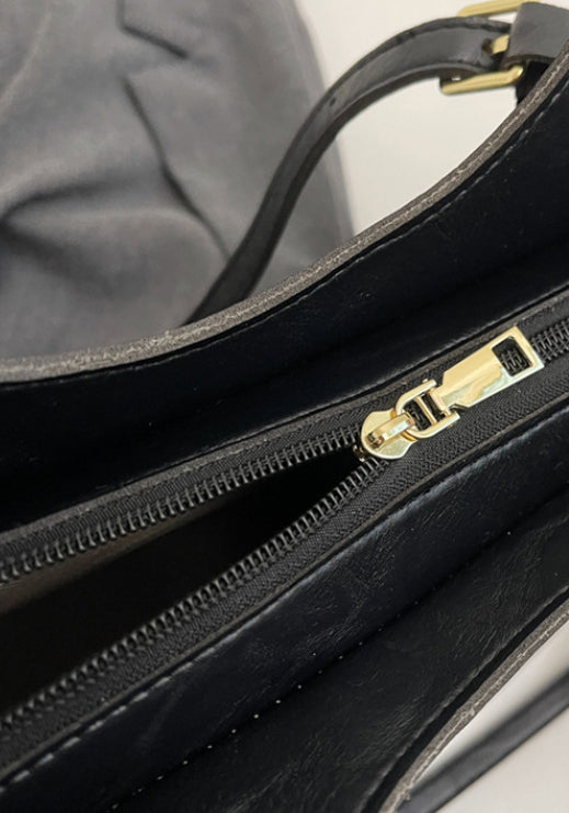 Detalle de cremallera dorada en bolso tote de cuero sintético negro con asa
