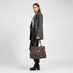 Bolso de cuero sintético con estampado leopardo visto de lado, asas marrones