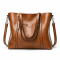 Bolso de hombro marrón con doble asa, bandolera extraíble y bolsillo frontal