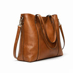 Bolso marrón de doble asa y bandolera, visto en ángulo lateral