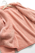 Chaqueta de pelo suave rosa extendida, con cremallera visible y textura rizada