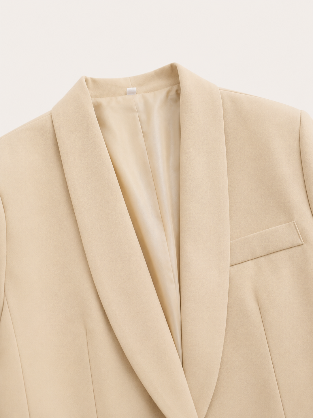 Detalle del blazer beige con solapas amplias y bolsillo de pecho