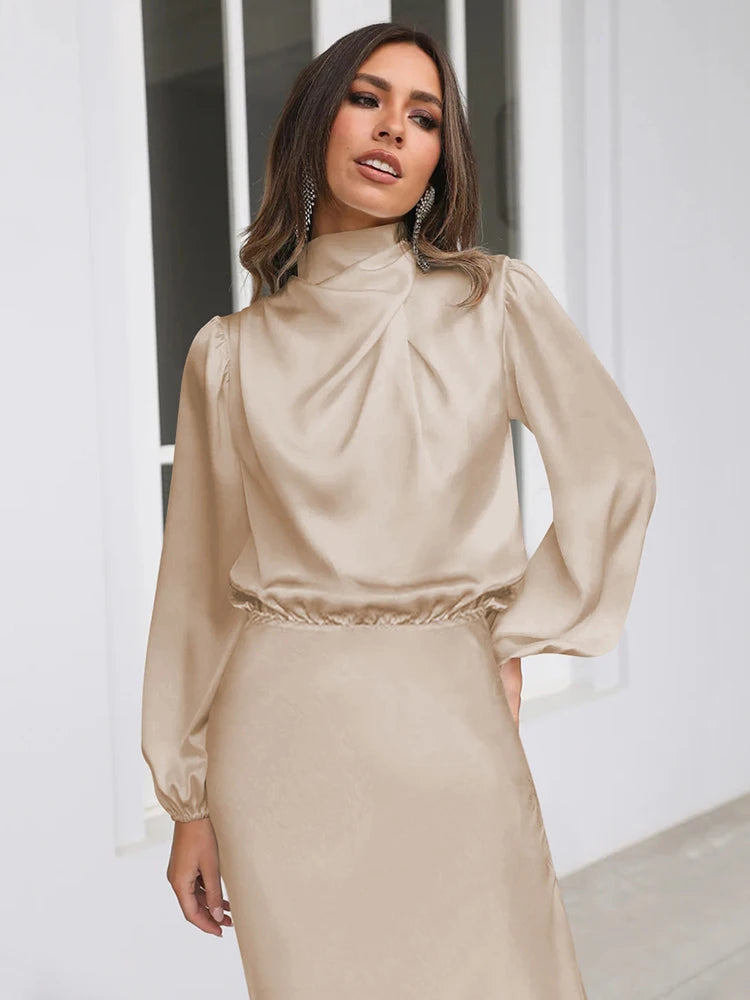 Beige satijnen midi-jurk met hoge draperende hals en lange mouwen, tailleband.