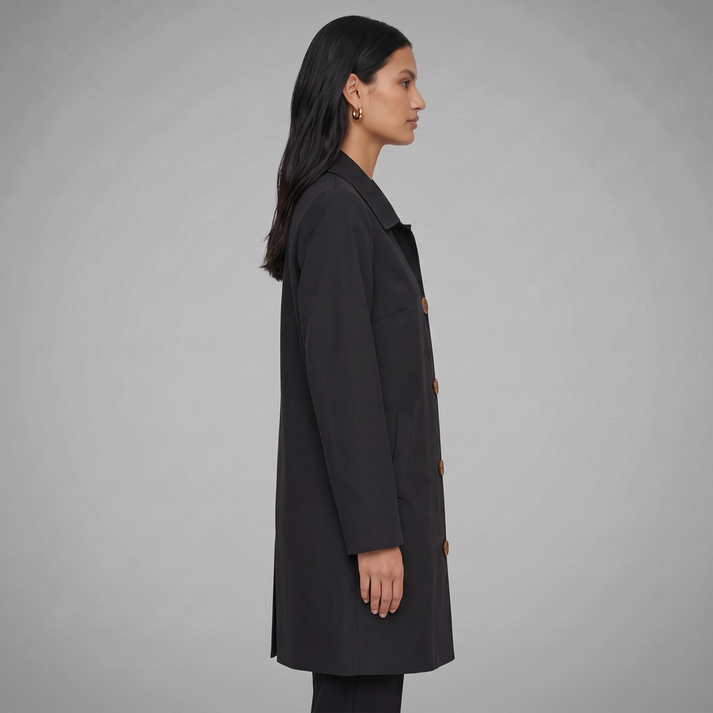 Gabardina midi negra de perfil, con mangas largas y cierre de botones