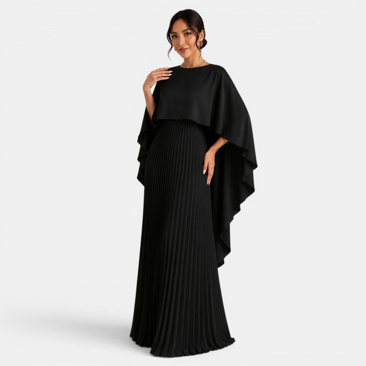 Vestido largo negro plisado con capa asimétrica de mangas murciélago, vista frontal.