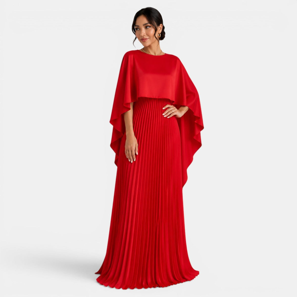 Vestido largo rojo con falda plisada y capa asimétrica de mangas murciélago, vista frontal.