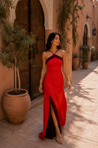 Vestido largo rojo halter con abertura lateral y diseño cruzado, falda entallada.