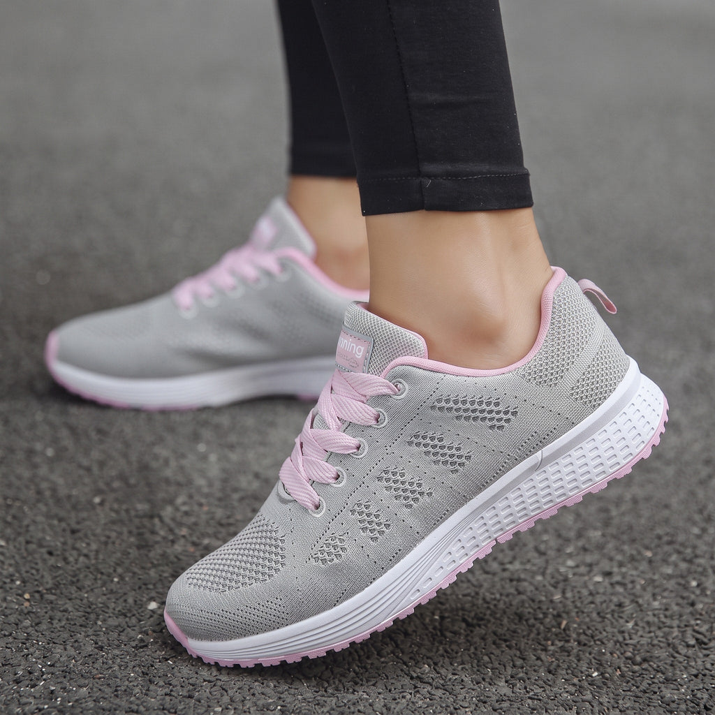 Zapatillas transpirables grises claras con cordones, detalles rosados y suela acolchada