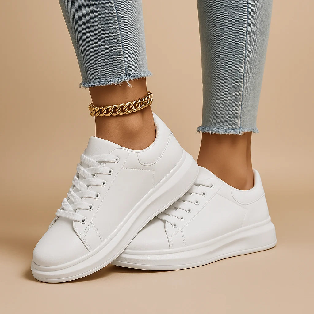 Zapatillas de piel blancas de caña baja con cordones y suela gruesa; pulsera dorada al tobillo