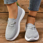 Zapatillas grises sin cordones con empeine de malla y suela blanca, vista lateral