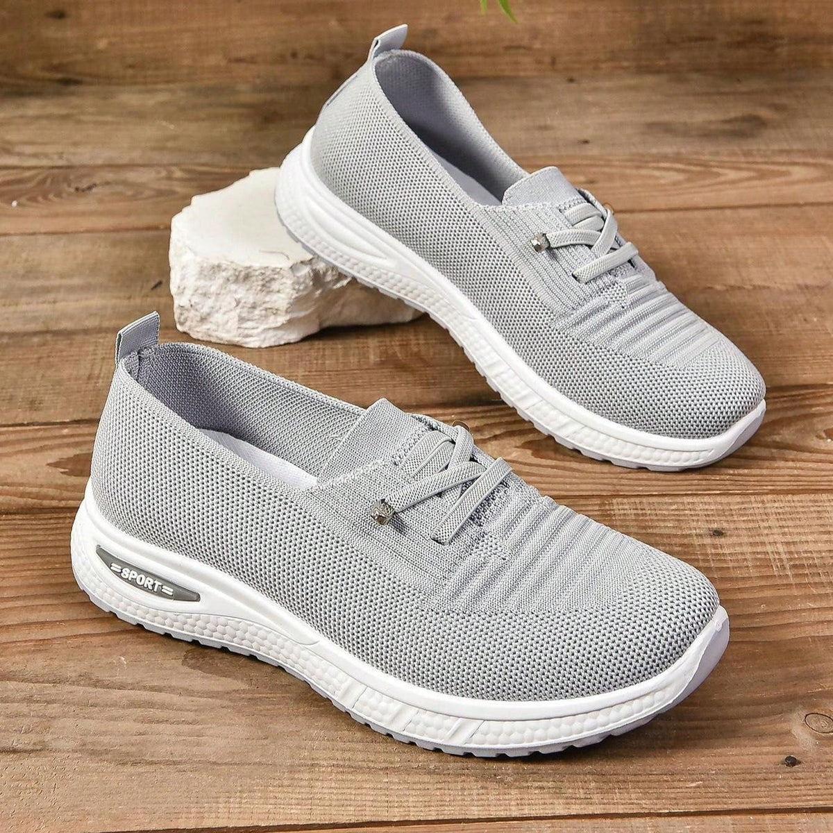 Zapatillas grises sin cordones con tejido transpirable, suela blanca y costuras visibles